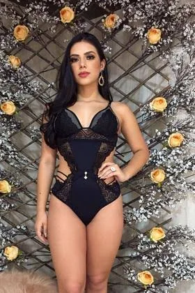 Mulher vestindo lingerie preta inteira em renda, com recortes laterais e tiras.