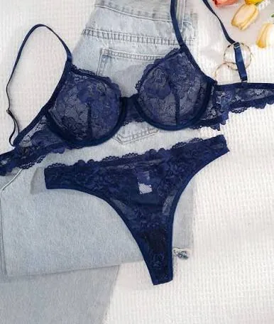 Conjunto de sutiã com aro e calcinha em renda azul-marinho sobre uma calça jeans clara.